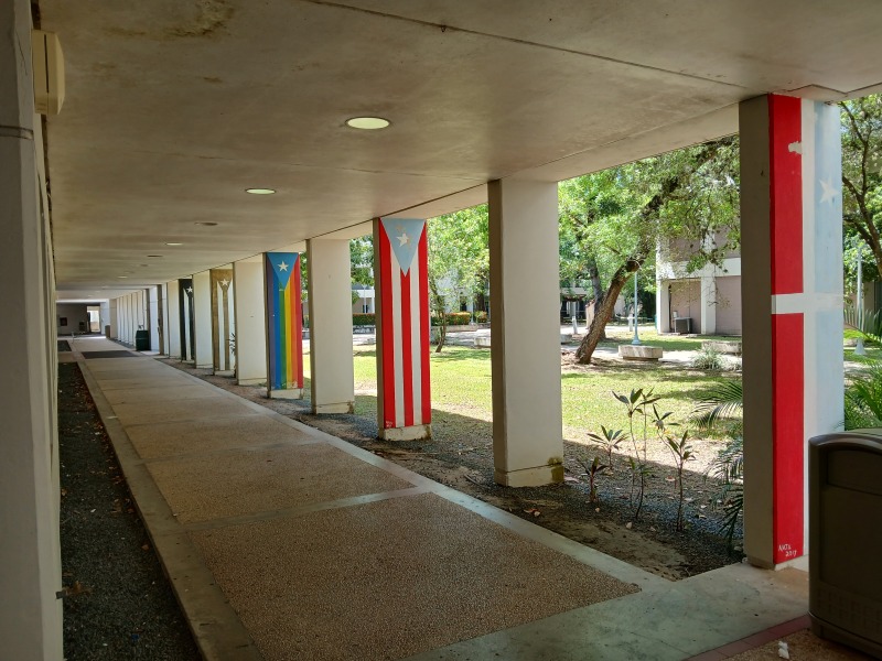 Photo of walkway with columns painted as different flags: Lares and different colors of puertorican flag.